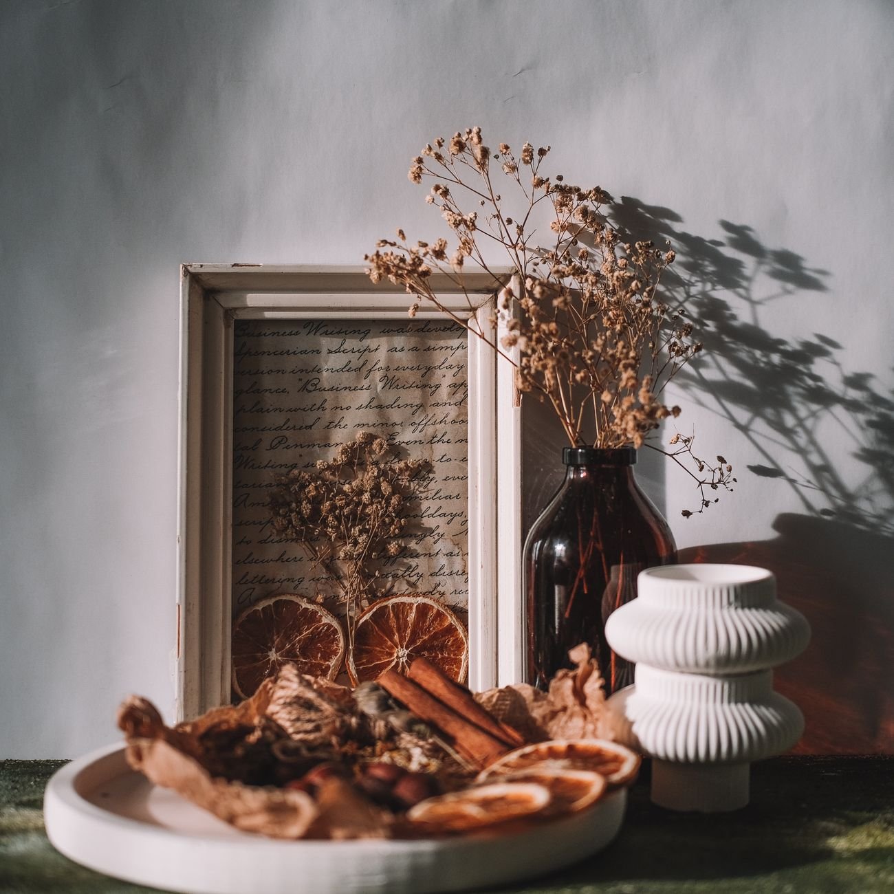Artistic still life featuring dried fruits and flowers with warm vintage aesthetics.